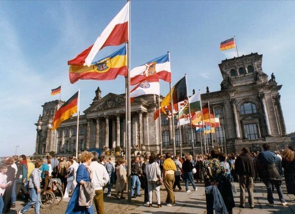 Bundesarchiv, Bild 183-1990-1003-417 / CC-BY-SA 3.0 Bild des Reichstages am 3. Oktober 1990 in Berlin: Um die schwarz-rot-goldene Fahne gruppieren sich vor dem Reichstagsgebäude die Fahnen aller Bundesländer Deutschlands.
